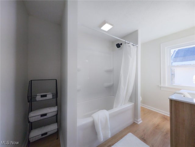 bathroom featuring vanity, shower / bath combo with shower curtain, wood finished floors, and baseboards