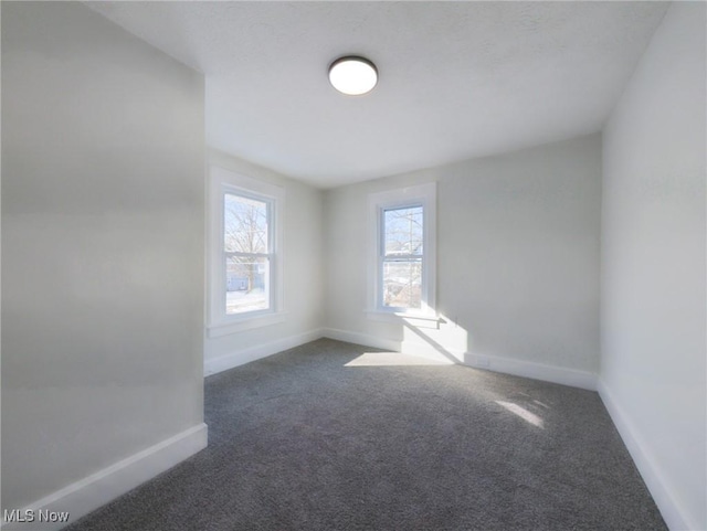 carpeted empty room featuring baseboards