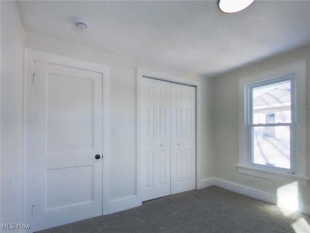 unfurnished bedroom with a closet, baseboards, and carpet flooring