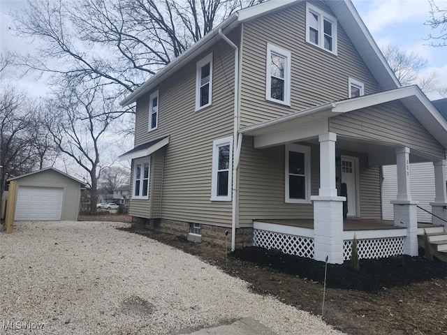 view of home's exterior featuring a detached garage, a porch, driveway, and an outdoor structure