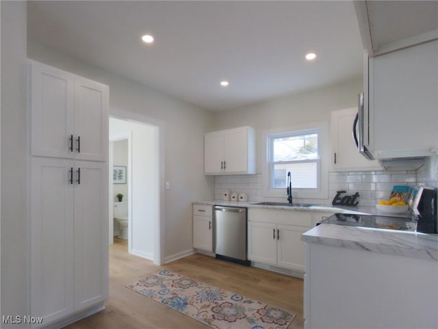 kitchen featuring dishwasher, light wood-style flooring, white cabinetry, and a sink