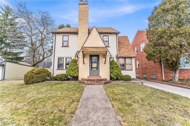 tudor-style house featuring a front yard and a chimney