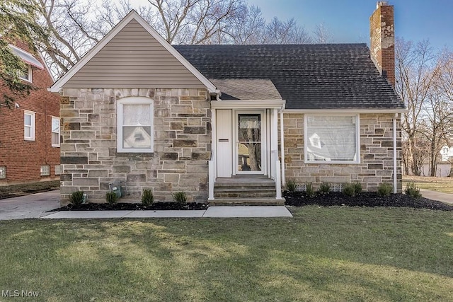 view of front facade with a shingled roof, a front lawn, stone siding, and a chimney