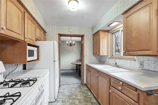 kitchen featuring wallpapered walls, white appliances, light countertops, and a sink