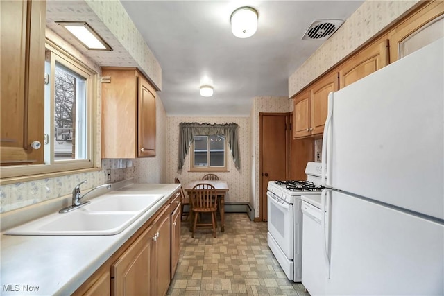 kitchen with visible vents, a sink, white appliances, wallpapered walls, and light floors