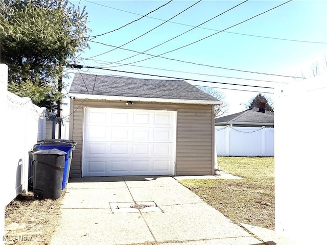 detached garage with concrete driveway and fence