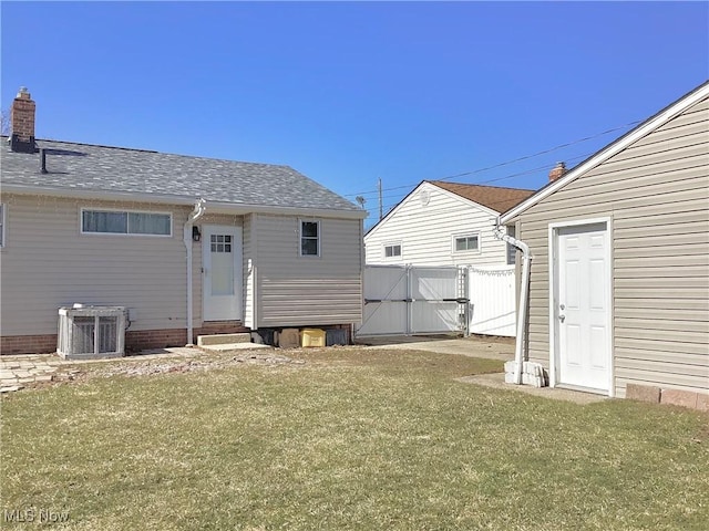 rear view of property featuring fence, entry steps, central AC, a yard, and a gate