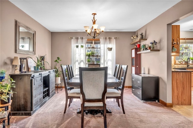 dining room featuring light colored carpet, baseboards, and a chandelier