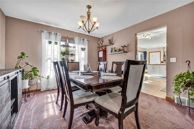 dining area with light carpet, baseboards, and an inviting chandelier