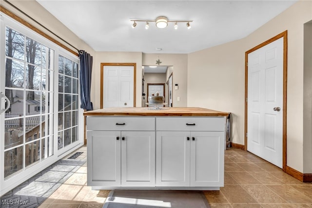 kitchen with white cabinetry, baseboards, visible vents, and wooden counters