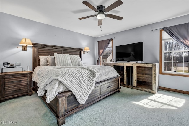 carpeted bedroom with multiple windows, a ceiling fan, and baseboards