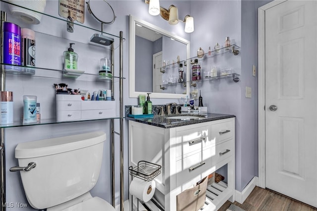 bathroom featuring toilet, vanity, baseboards, and wood finished floors