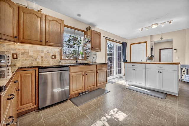 kitchen featuring visible vents, a sink, backsplash, stainless steel dishwasher, and dark stone counters