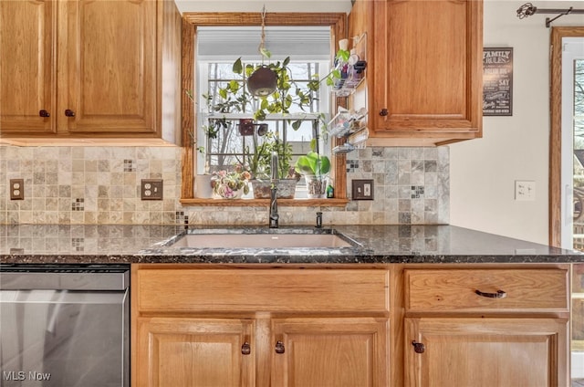 kitchen with backsplash, dark stone countertops, dishwasher, and a sink