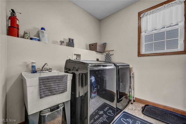 clothes washing area featuring laundry area, washing machine and dryer, baseboards, and a sink