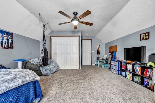 carpeted bedroom with a closet, a textured ceiling, and lofted ceiling