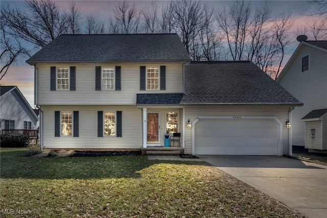 view of front of property with an attached garage, driveway, a yard, and roof with shingles