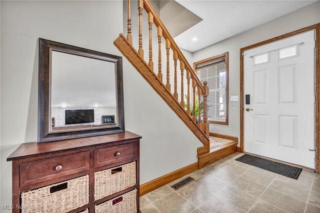 foyer with stairway, baseboards, and visible vents