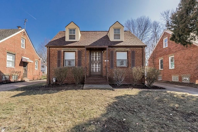 cape cod house with brick siding, a shingled roof, and a front yard