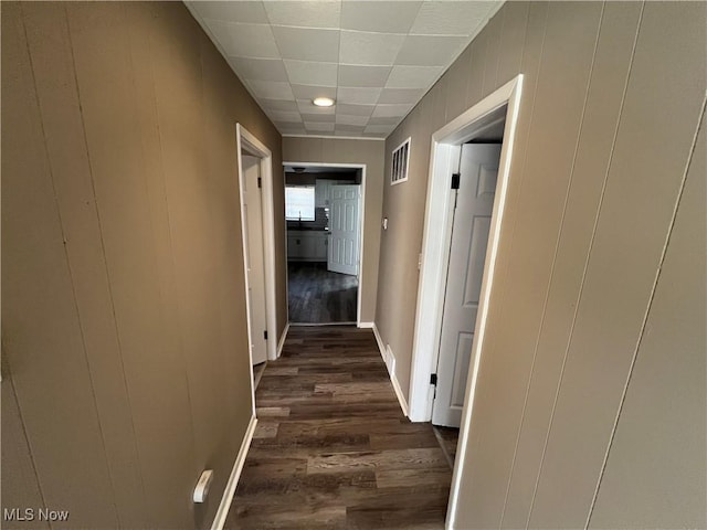 hall featuring wooden walls, dark wood-style floors, and visible vents