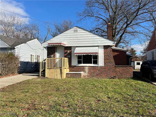 bungalow-style home with a front yard, brick siding, and a chimney