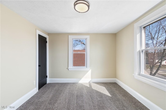 carpeted spare room with baseboards and a textured ceiling