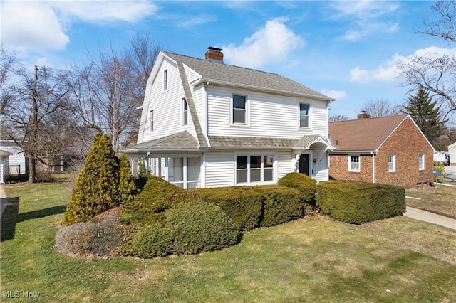 view of front of house with a gambrel roof, a chimney, a front lawn, and roof with shingles