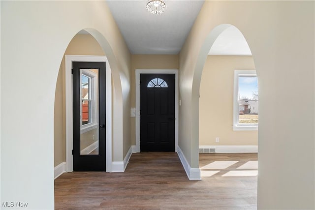 entryway featuring visible vents, baseboards, and wood finished floors