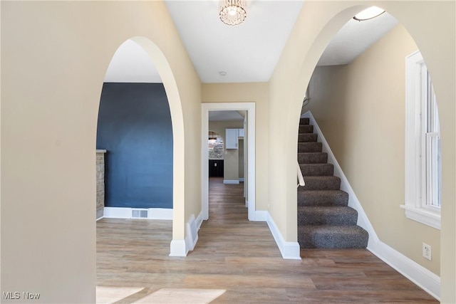 foyer entrance with stairway, wood finished floors, visible vents, and baseboards