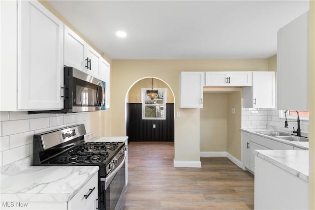 kitchen with light wood-style flooring, white cabinets, stainless steel appliances, and a sink