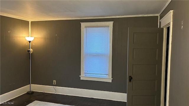 spare room featuring wood finished floors, baseboards, and ornamental molding