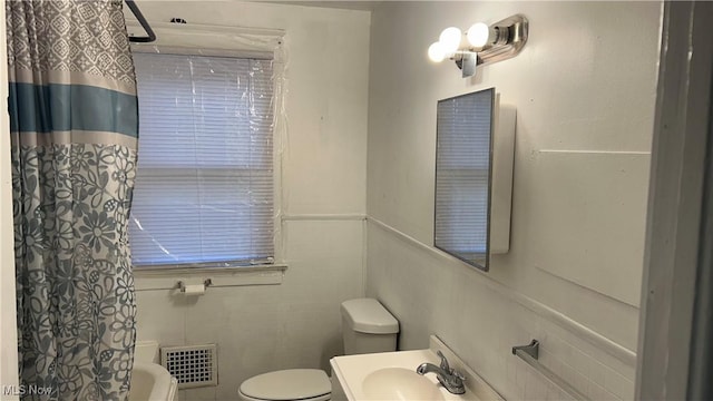 bathroom featuring vanity, tile walls, toilet, and visible vents