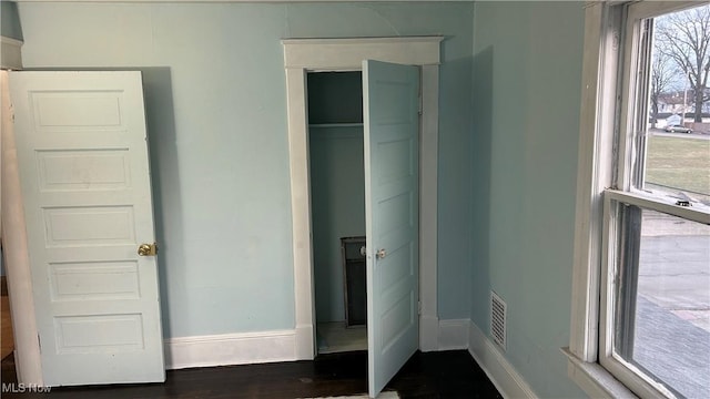 unfurnished bedroom with visible vents, baseboards, and dark wood-type flooring