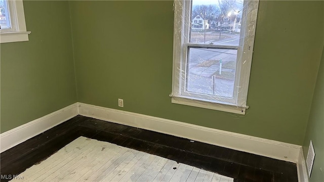 spare room featuring dark wood-style floors and baseboards