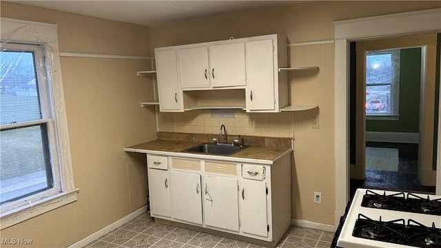 kitchen featuring decorative backsplash, a sink, white range with gas cooktop, and open shelves