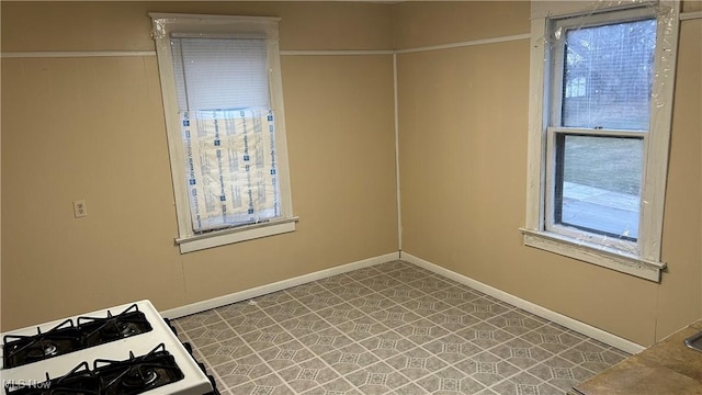 interior space with tile patterned floors, baseboards, and white gas range