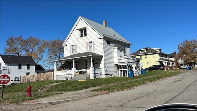 view of front of home featuring a residential view, covered porch, a front lawn, and fence