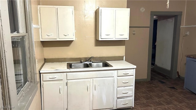 kitchen with light countertops, white cabinets, and a sink