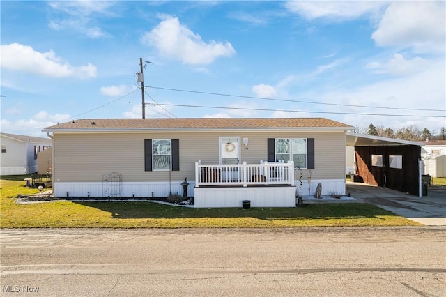 manufactured / mobile home with a carport, a porch, concrete driveway, and a front lawn