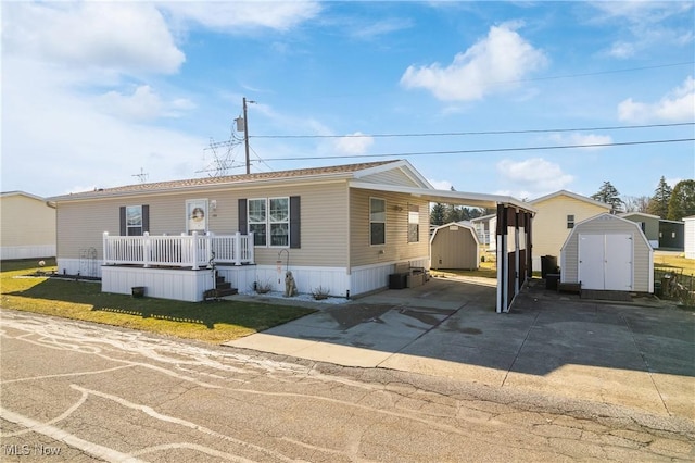 manufactured / mobile home featuring an attached carport, an outdoor structure, concrete driveway, and a shed