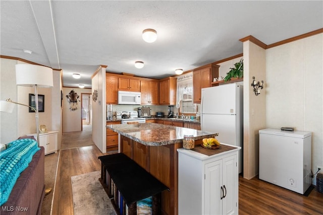 kitchen featuring a sink, white appliances, dark wood finished floors, and a center island