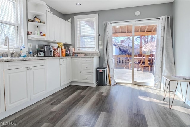 kitchen featuring open shelves, dark wood-type flooring, plenty of natural light, white cabinetry, and a sink