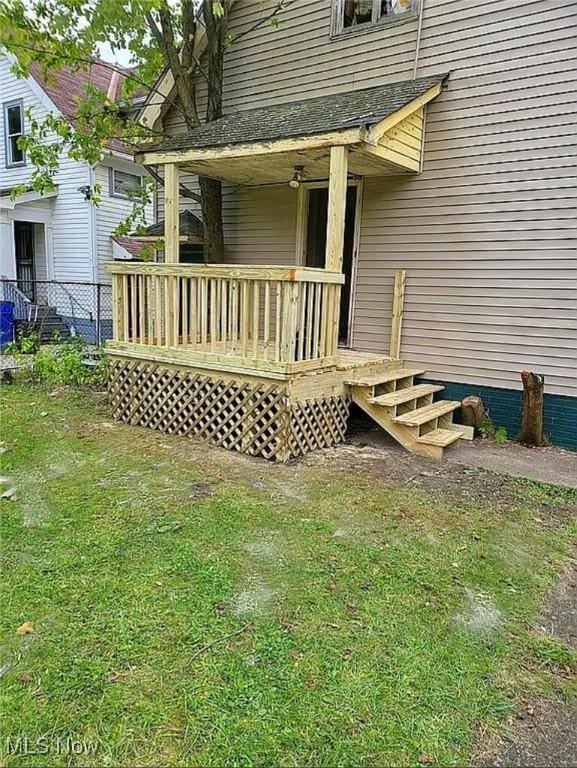 doorway to property featuring a lawn, a wooden deck, and fence