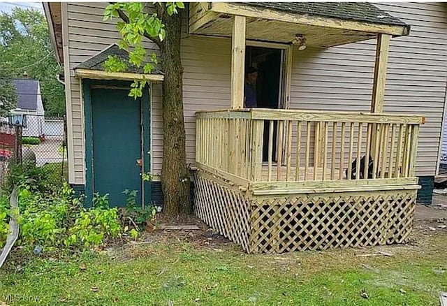 view of exterior entry featuring a wooden deck and fence