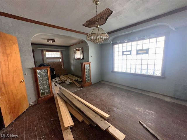 unfurnished dining area featuring arched walkways and crown molding