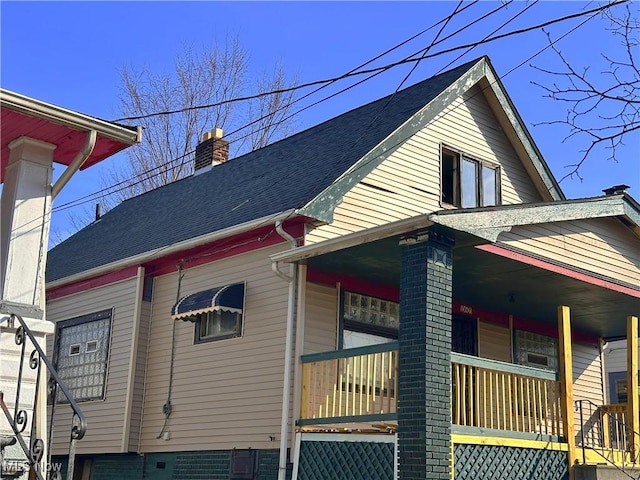 view of home's exterior featuring covered porch, a chimney, and a shingled roof