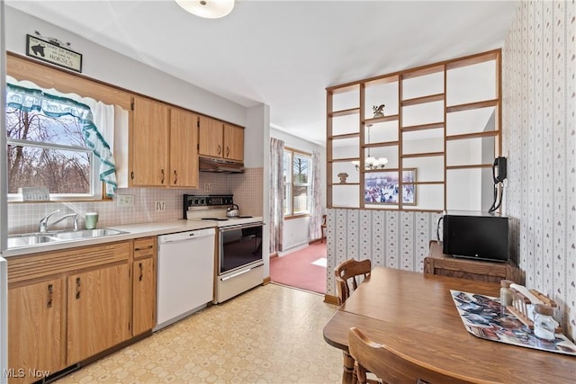 kitchen featuring wallpapered walls, white appliances, under cabinet range hood, and a sink