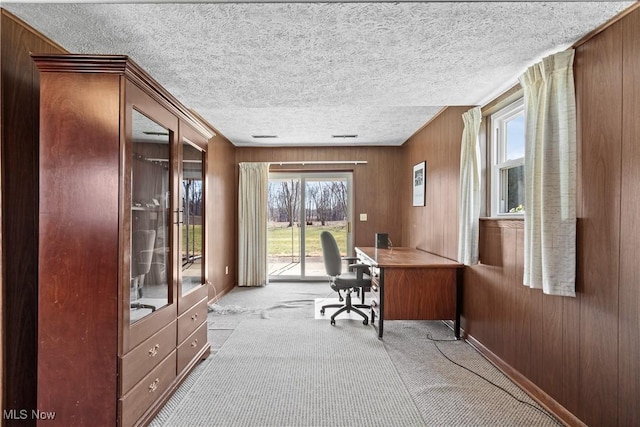 home office featuring carpet, baseboards, wood walls, and a textured ceiling