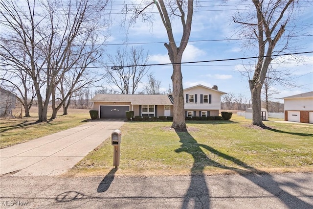 split level home featuring a chimney, an attached garage, concrete driveway, and a front yard