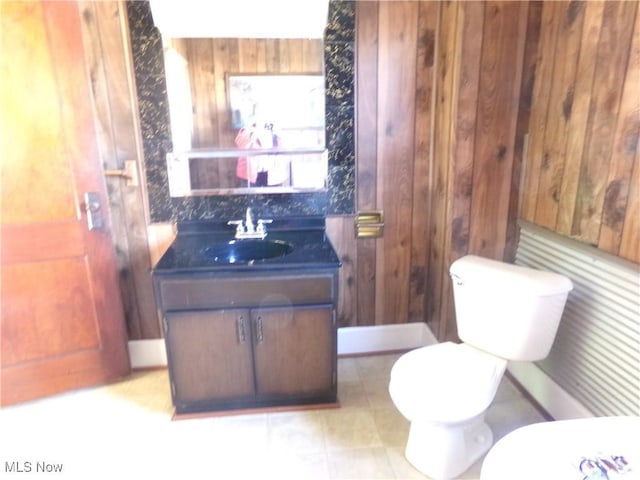 half bathroom with wood walls, vanity, and toilet